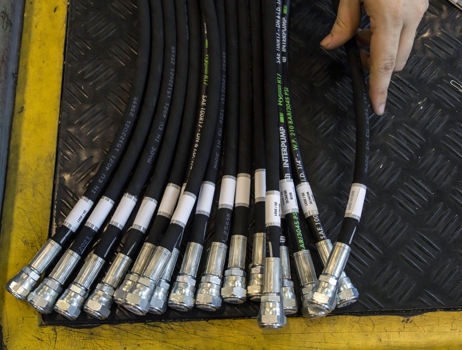 An image of several hydraulic hose assemblies with labels attached near the fittings in a pile.